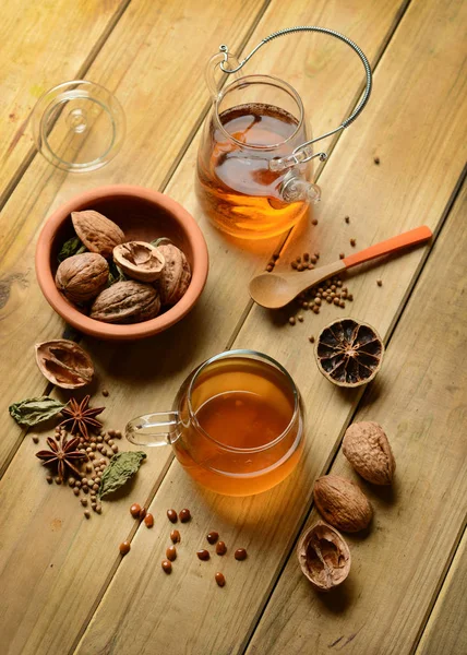 Herbal tea with walnuts and ingredients around — Stock Photo, Image