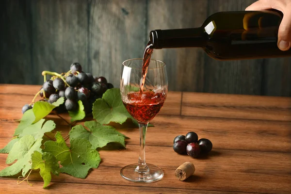 Pour red wine into the glass - wood background - closeup — Stock Photo, Image