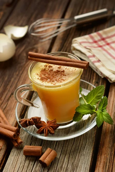 Eggnog into glass cup on wooden table — Stock Photo, Image