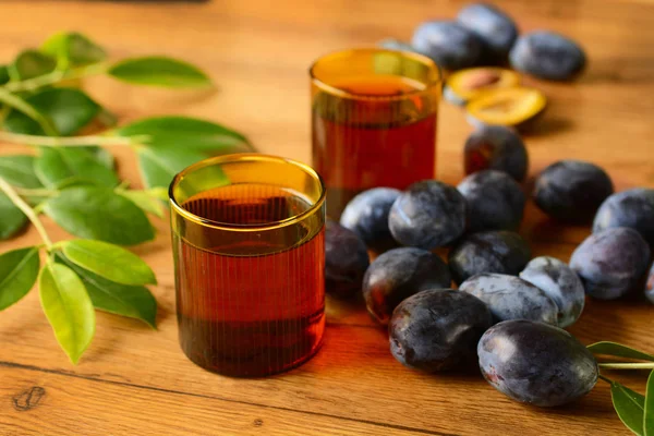 Plum juice in glasses with fruit around — Stock Photo, Image