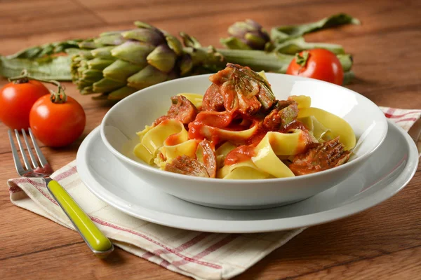 Tagliatelle with artichoke and tomato sauce in white plate — Stock Photo, Image