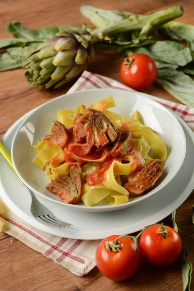 Tagliatelle with artichoke and tomato sauce in white plate — Stock Photo, Image