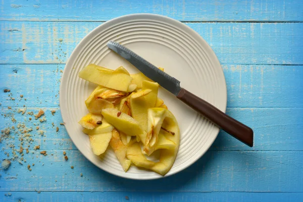 Apple peels on white plate - blue table — Stock Photo, Image