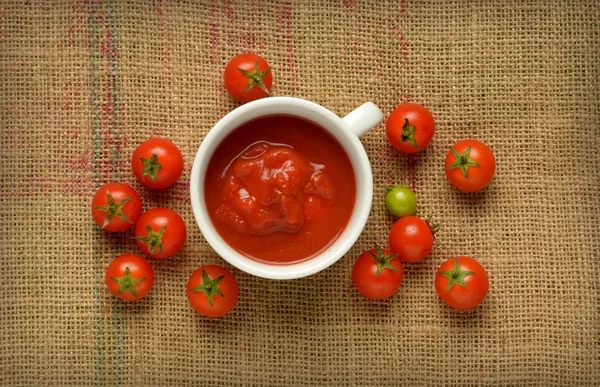 Salsa de tomate cherry en la taza blanca - lona de yute — Foto de Stock