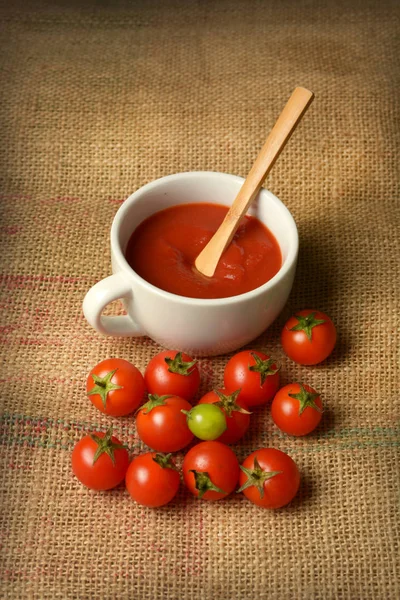 Sauce tomate cerise dans la tasse blanche - toile de jute — Photo
