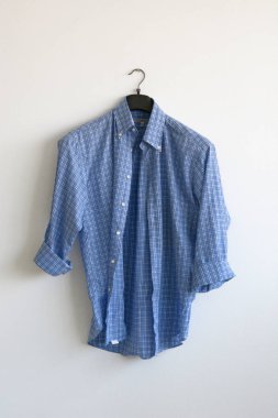 Beyaz duvarda asılı ışık mavi gömlek