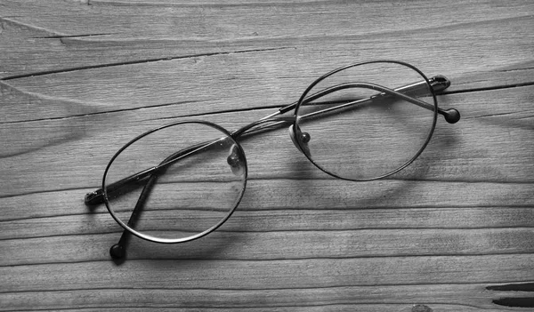 Óculos velhos na mesa de madeira - preto e branco — Fotografia de Stock