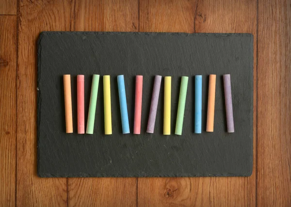 Pile of colored chalks on slate panel — Stock Photo, Image