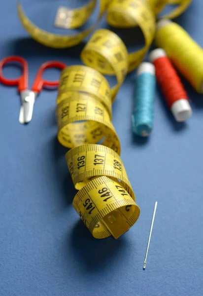 Utensilios de coser sobre fondo azul - cinta métrica, tijeras, cuna —  Fotos de Stock