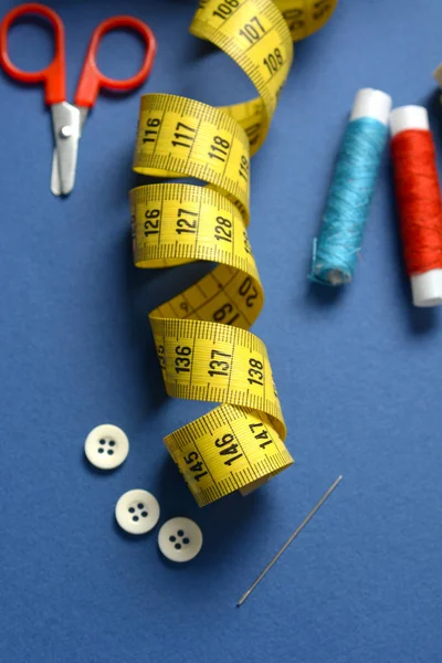 Utensilios de coser sobre fondo azul - cinta métrica, tijeras, cuna —  Fotos de Stock