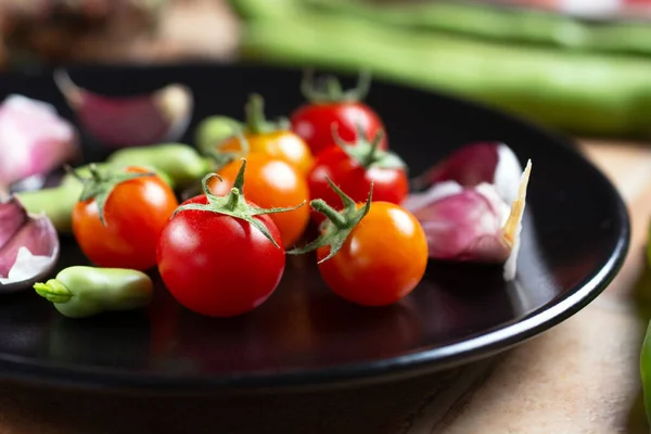 Pomidor Wiśniowy Bób Czosnek Czarnym Naczyniu Zbliżenie — Zdjęcie stockowe