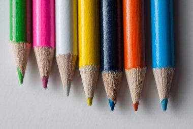 Bir grup beyaz bir yüzeye çok renkli kalemler Close-Up