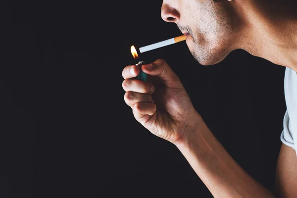 Primo piano di un uomo che accende una sigaretta in un'atmosfera buia — Foto Stock
