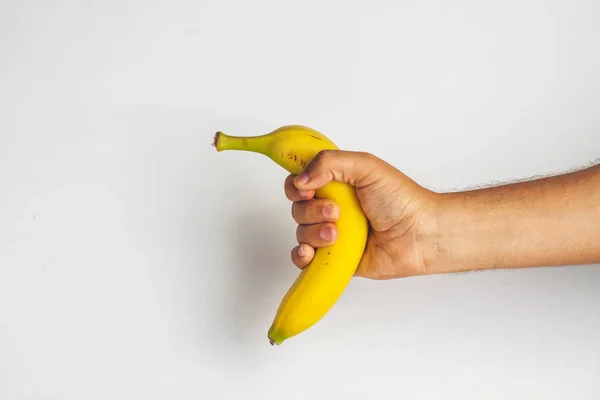 Main tenant une banane sur fond blanc — Photo