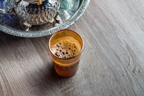 close up of a moroccan glass of tea on a wooden table