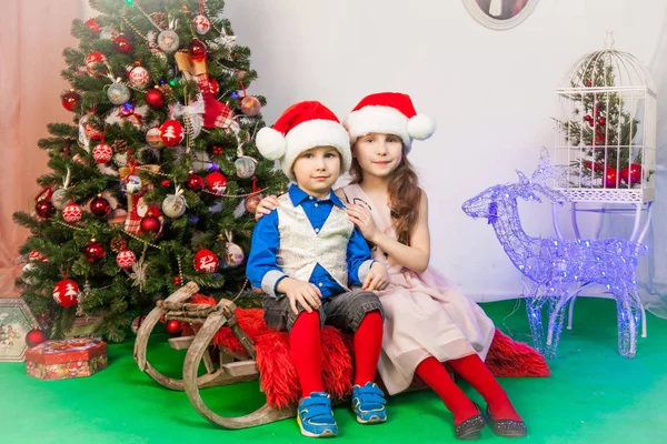 Usměvavý chlapec a dívka v ateliéru v novoroční dekorace — Stock fotografie