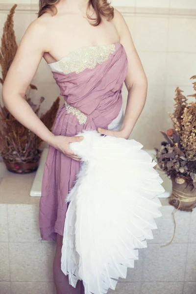 Frau in weißem Kleid mit lila Gürtel und Engelsflügel in der Hand — Stockfoto