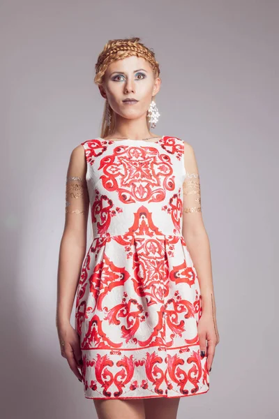 Young girl in white dress with ethnic pattern of red color — Stock Photo, Image