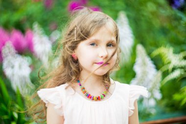 Bir kolye boncuk boynuna, mor ruj dudakları yeşil yeşillik çerçevede bir genç kızla