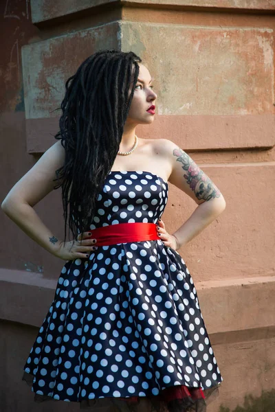 Young girl in vintage black dress in white peas with black dreadlocks on head and red lipstick on lips — Stock Photo, Image