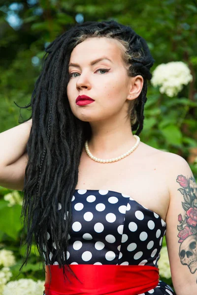 Young girl in vintage black dress in white peas with black dreadlocks on head and red lipstick on lips — Stock Photo, Image