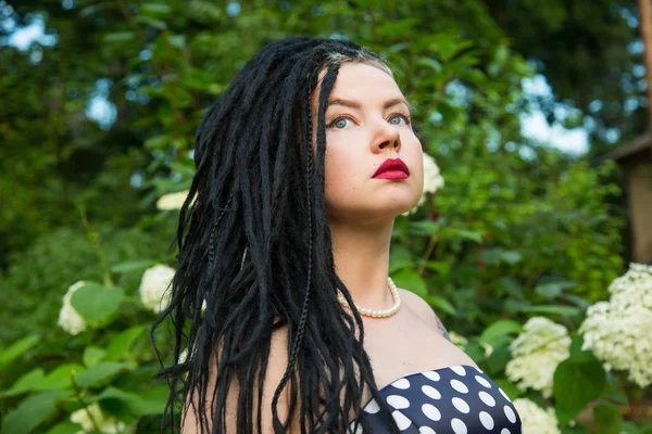 Young girl in vintage black dress in white peas with black dreadlocks on head and red lipstick on lips — Stock Photo, Image