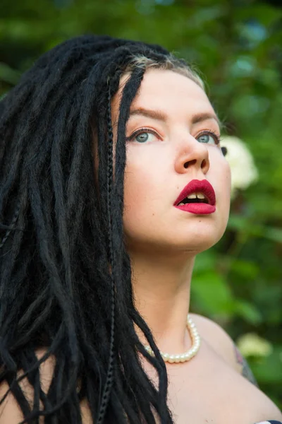 Jeune fille en robe noire vintage en pois blancs avec dreadlocks noirs sur la tête et rouge à lèvres rouge sur les lèvres — Photo