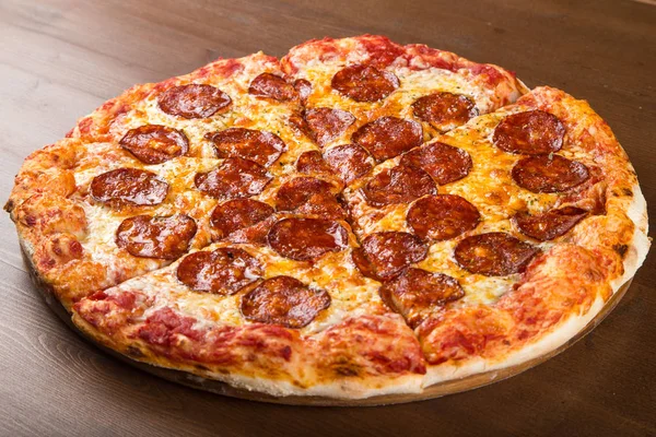 Coupé en morceaux de pizza saucisse, salami et fromage sur un plateau en bois — Photo