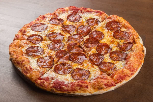 Coupé en morceaux de pizza saucisse, salami et fromage sur un plateau en bois — Photo