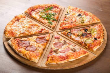 Ahşap bir tepside farklı dolguları ile çeşitli pizza