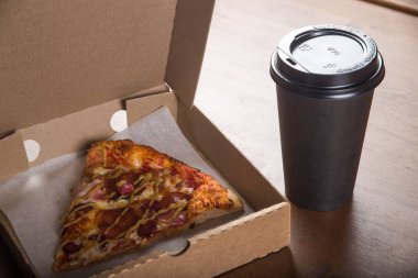 bir parça pizza bireysel bir karton kutu ve kahve için plastik bir kap içinde