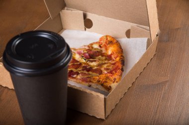 bir parça pizza bireysel bir karton kutu ve kahve için plastik bir kap içinde