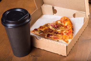 bir parça pizza bireysel bir karton kutu ve kahve için plastik bir kap içinde