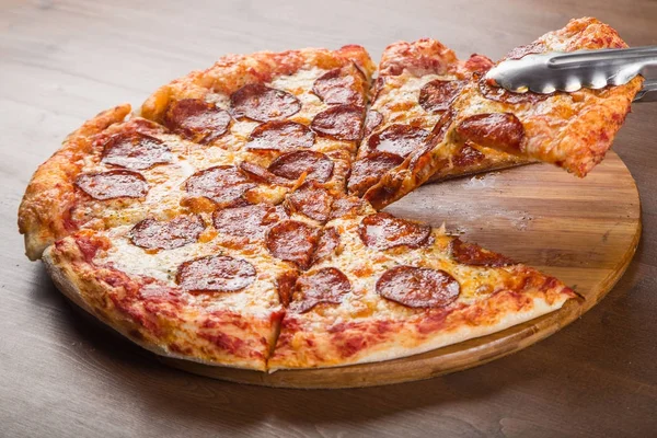 Gesneden in stukken pizza worst, salami en kaas op een houten schotel — Stockfoto