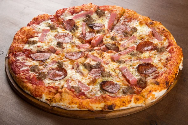 Coupé en morceaux de pizza saucisse, salami et fromage sur un plateau en bois — Photo