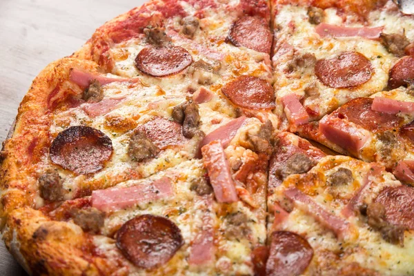 Coupé en morceaux de pizza saucisse, salami et fromage sur un plateau en bois — Photo