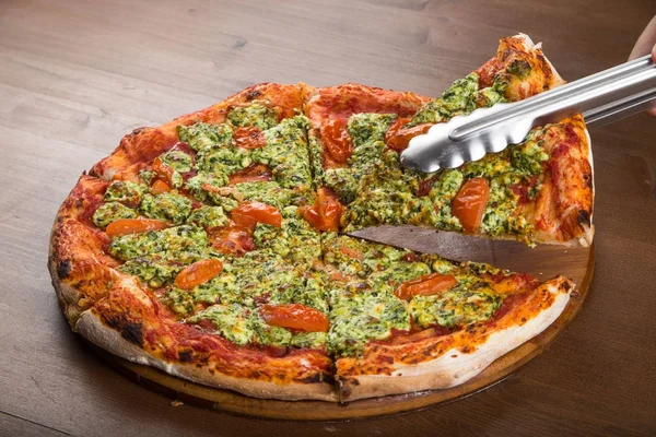 Ut în bucăți pizza cu șuncă, arugula și verdeață pe o tavă de lemn — Fotografie, imagine de stoc