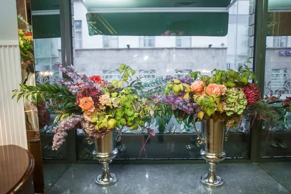 Металлические вазы в виде кубка с букетами цветов находятся на подоконнике — стоковое фото