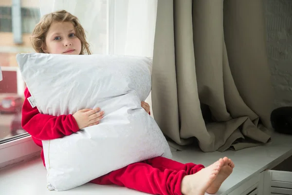 Meisje in de rode pyjama met een sneeuwwitte kussen — Stockfoto