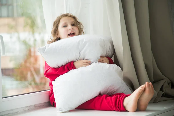 Meisje in de rode pyjama met een sneeuwwitte kussen — Stockfoto