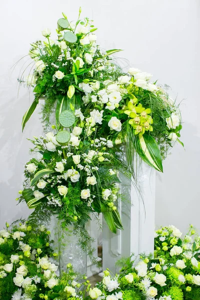 En bukett med vita rosor, gula påskliljor, grönska och lotusblommor står i en vas på en marmor stå — Stockfoto
