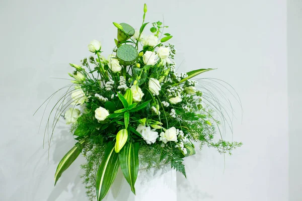 Букет з білих троянд, жовтих нарцисів, зелені та лотосів стоїть у вазі на мармуровій підставці — стокове фото