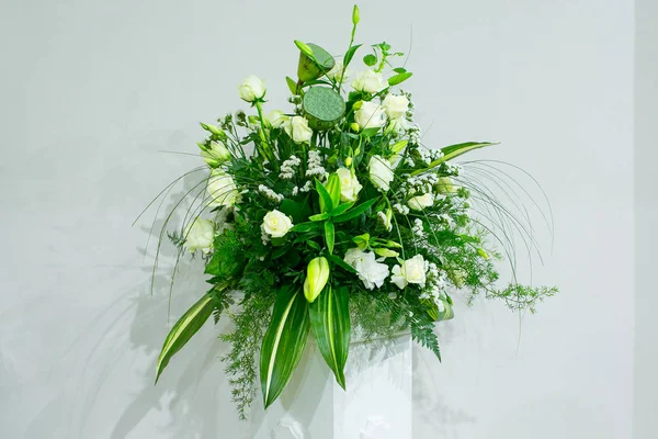 Букет з білих троянд, жовтих нарцисів, зелені та лотосів стоїть у вазі на мармуровій підставці — стокове фото