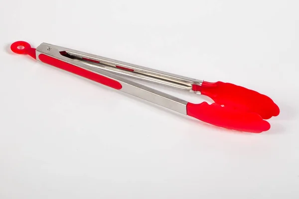 Metal kitchen tongs with red silicone parts — Stock Photo, Image