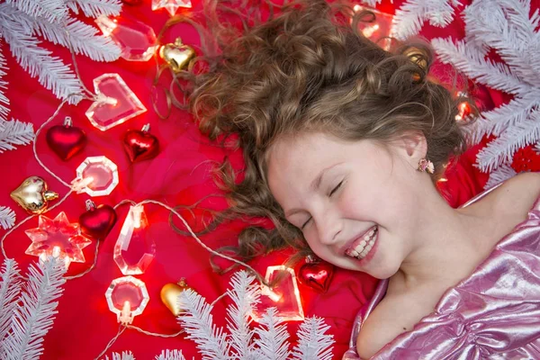 Маленька Чарівна Дівчинка Лежить Червоній Підлозі Різдвяною Гірляндою Ялинковими Гілками — стокове фото