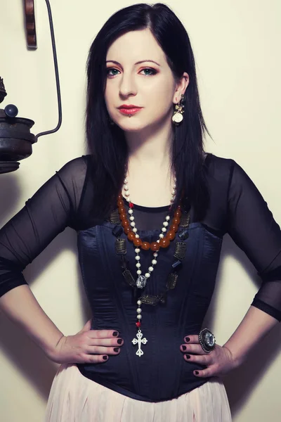 portrait of a young beautiful Polish girl with green eyes dressed in a corset against the background of a vintage coffee grinder