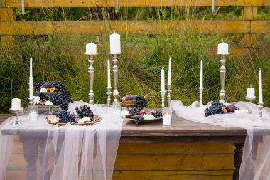 bahçesinde meyve ve mumlar sahip kanalları bulunan bir yemek masası