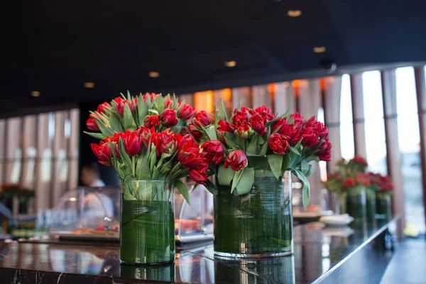 red tulips in a large glass vase