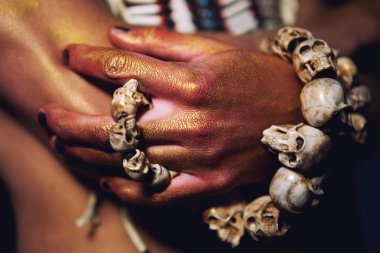 bir adam elinde bir bilezik kafatasları ile