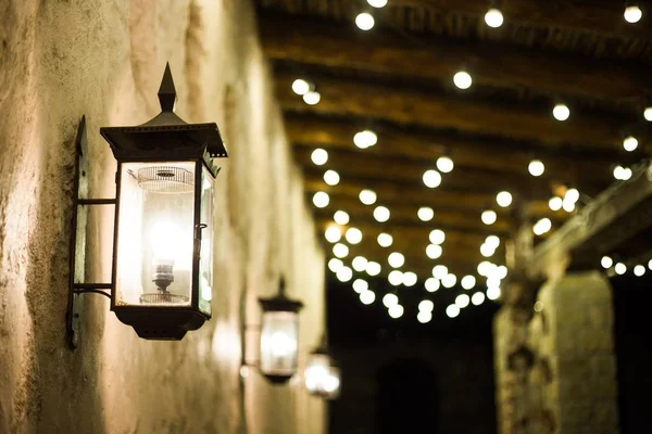 The lane between the old houses is lit by a vintage lantern and garlands